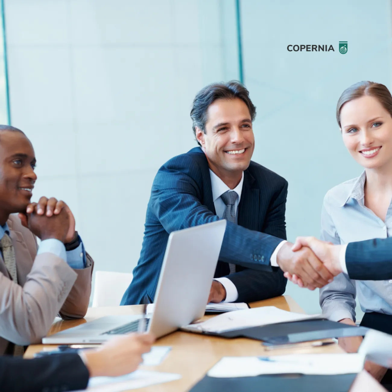 There are three executives sitting with one shaking hands with an applicant